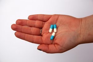 A persons hand holding three antiobiotic tablets.